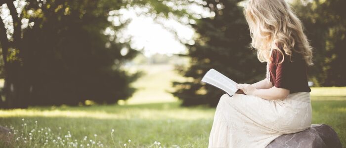 Girl reading a book outside preventing summer slide