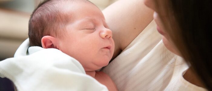 Newborn baby in mother's arms - Caring for a Newborn During Cold and Flu Season post